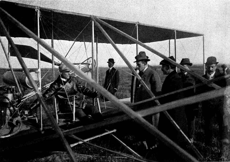 Illustration:
Wilbur Wright: Zeigt dem König von Spanien, wie er bei Beginn des Starts mit
der rechten Hand den Sperrhebel löst, der die durch das Fallgewicht im Zug
befindliche Flugmaschine frei gibt.