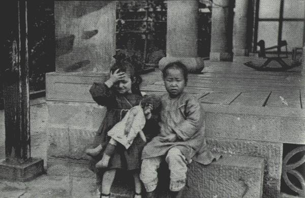 WHERE EAST MEETS WEST

Playfellows in Far Interior China. The little white girl is the daughter
of a missionary in Suifu, Szech'uan, where picture was taken on porch of
mission residence.