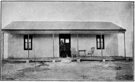 LA PREMIÈRE MAISON DE LA «COLONIA CERVANTES», EN BOIS,
DÉMONTABLE, REVÊTUE DE TÔLES DE ZINC ONDULÉ

Blasco a été photographié sur le seuil de cette baraque