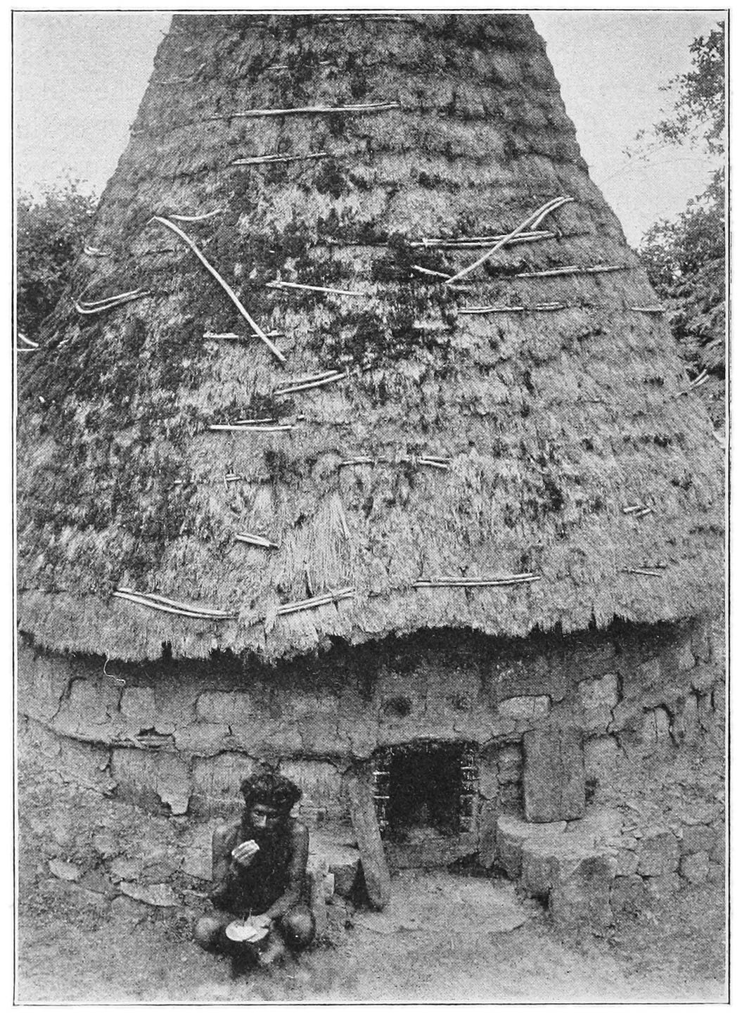 FIG. 14.—THE LOWER PART OF THE CONICAL DAIRY OF NÒDRS, WHICH IS HIDDEN BY THE WALL IN FIG. 13. THE ‘WURSOL’ IS SHOWN EATING ‘AL’ FROM A LEAF-PLATE.